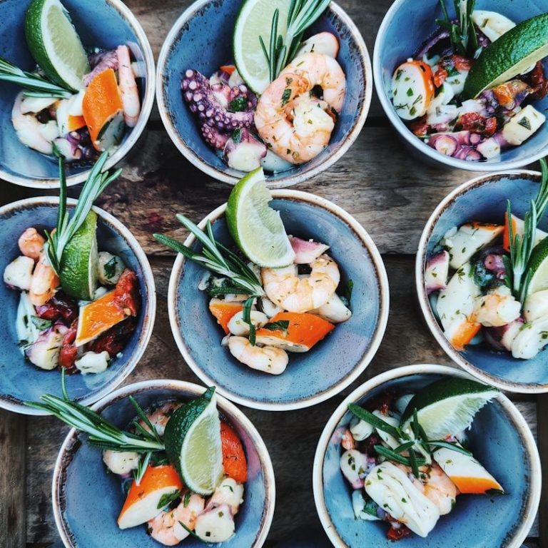 Fingerfood Vielfältige Meeresfrüchte in Schalen, garniert mit Limettenscheiben und Kräutern. Fingerfood