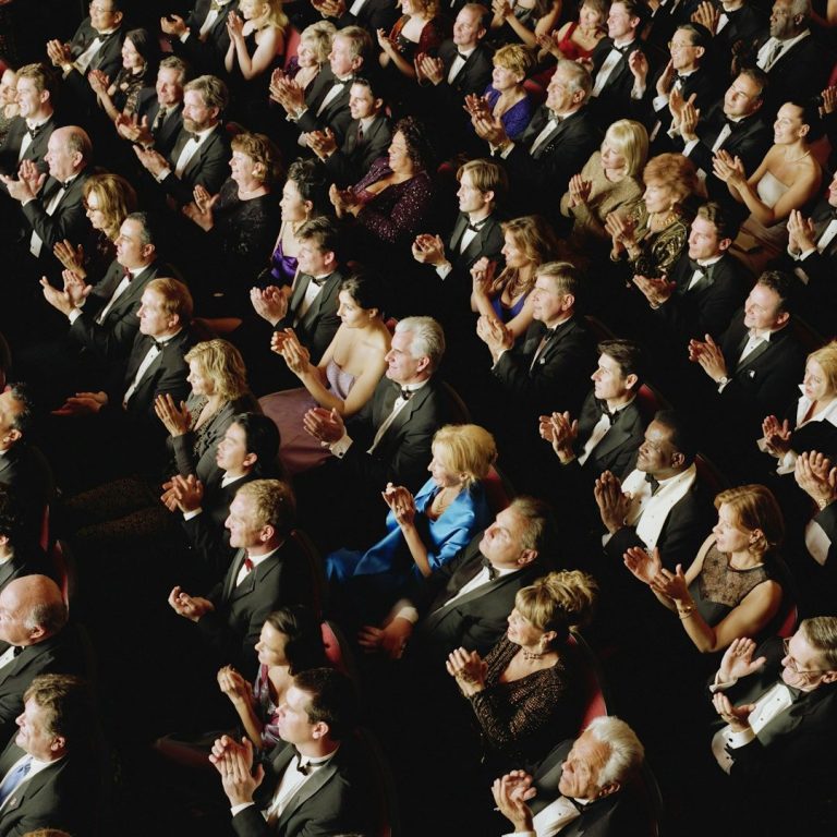 Tagungs Catering Eine Menge von elegantly gekleideten Menschen, die applaudieren in einem festlichen Veranstaltungsort.