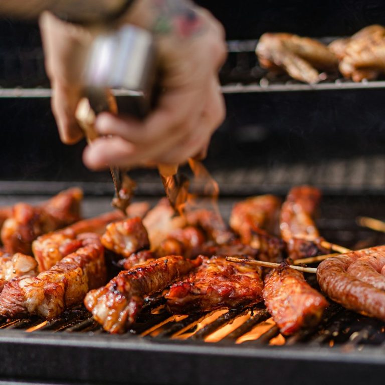 Grill BBQ Angebote mit link Gegrilltes Fleisch auf einem Grill, mit einer Hand, die Gewürze darüber streut.